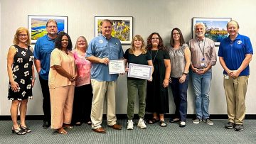 District Executive Director Mike Register (center) presents the October Employee of the Month award to Katie Von Canal at the Palm Bay Service Center, with service center staff joining in the presentation.