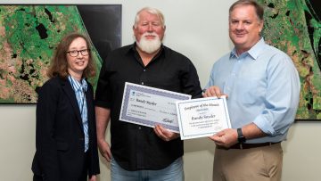 District Executive Director Mike Register (right) and Assistant Executive Director Mary Ellen Winkler present the March Employee of the Month award to Randy Snyder.