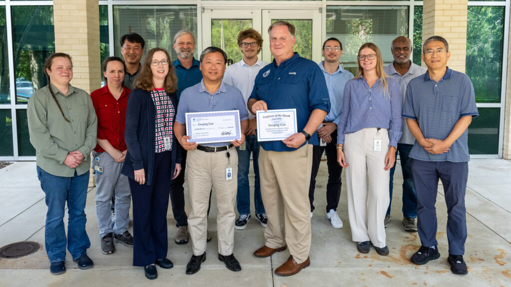Group of people with two center people holding a certificate and ceremonial check